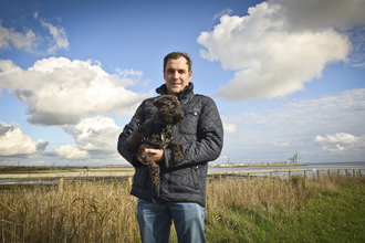 David holding his dog at a wetland