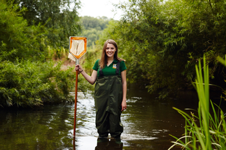 Sophie standing in a river with a net