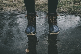 Photo of a person in walking boots walking through puddles