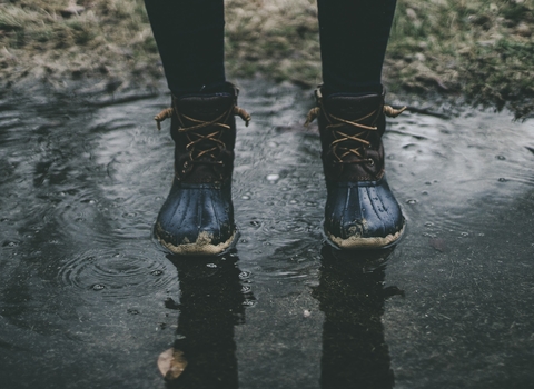 Photo of a person in walking boots walking through puddles