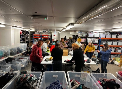 Photo of eight people sorting textiles into plastic boxes.