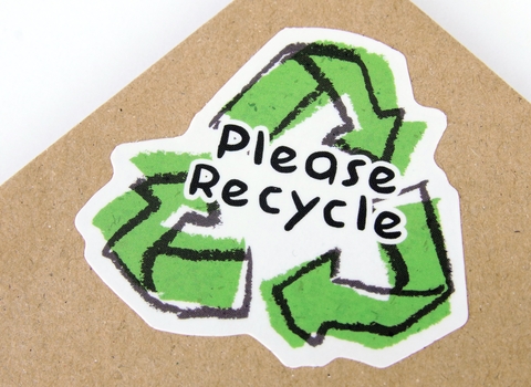 Photo of a sticker with the recycle symbol saying please recycle